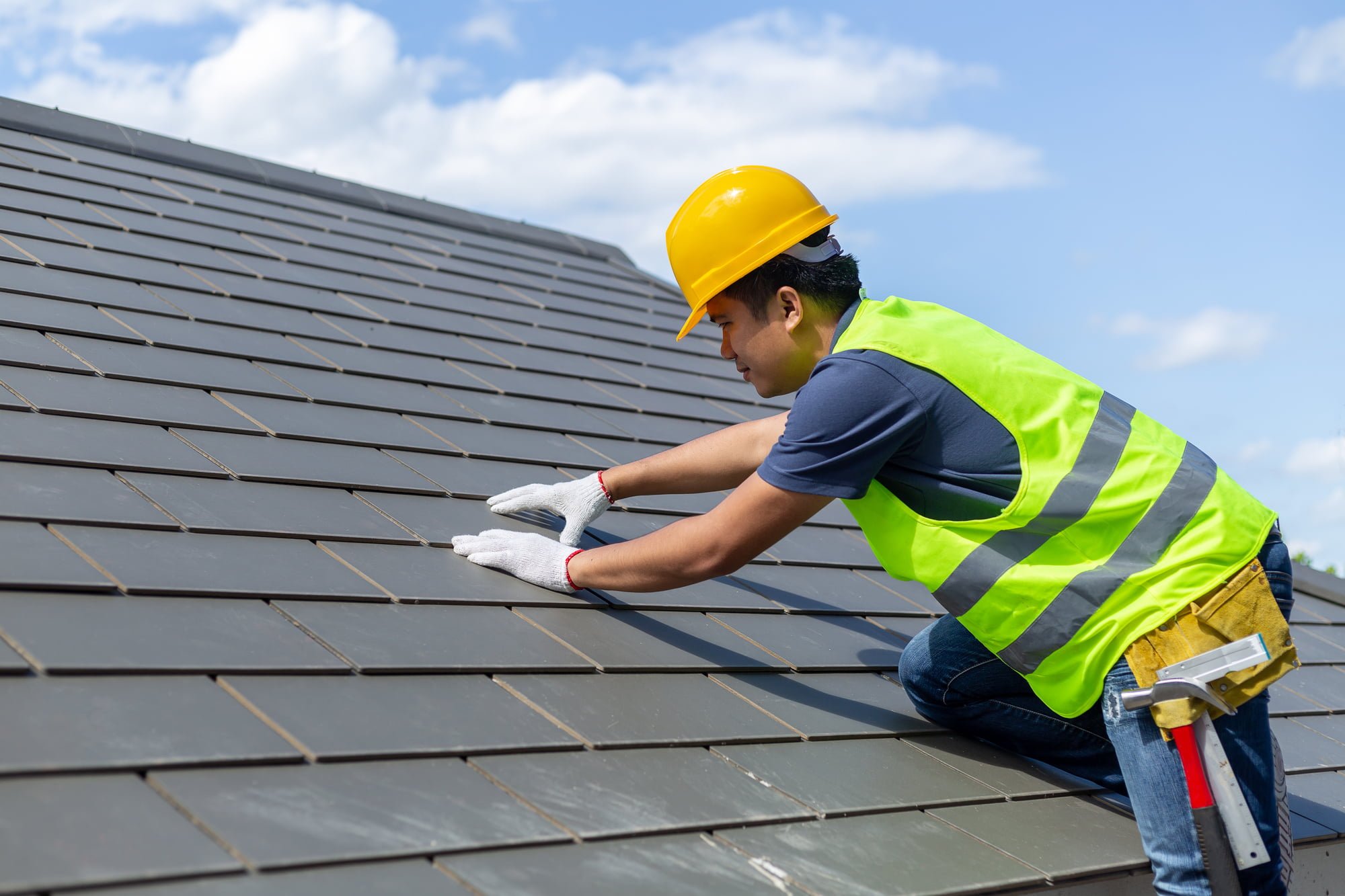 Roof Repair, Worker With White Gloves Replacing Gray Tiles Or Shingles On House With Blue Sky As Background And Copy Space, Roofing Construction Worker Standing On A Roof Covering It With Tiles.
